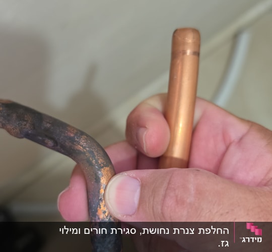 יד מחזיקה צינור נחושת עם סימני חלודה
